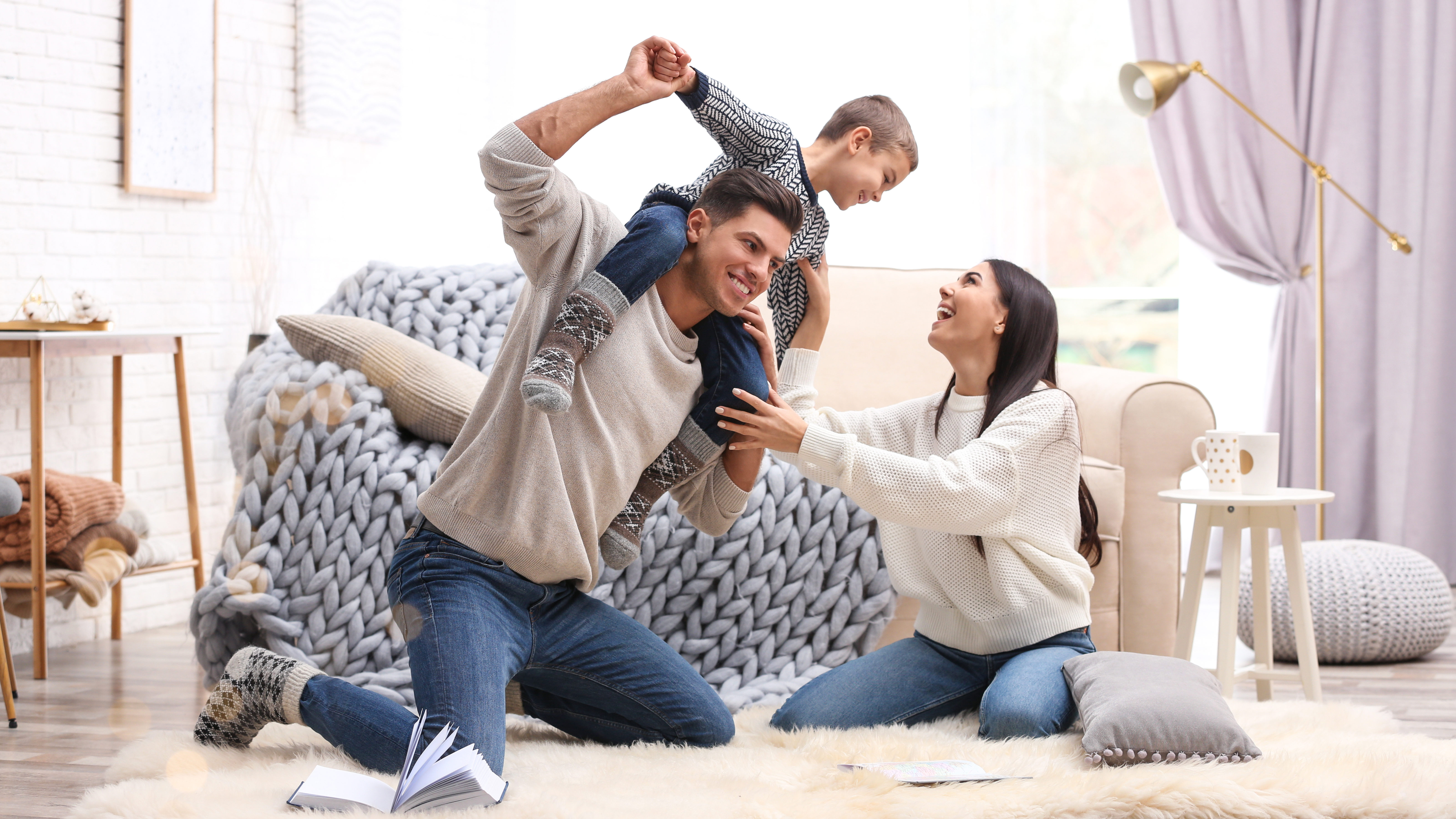 Junge Eltern spielen mit Sohn auf dem Teppich